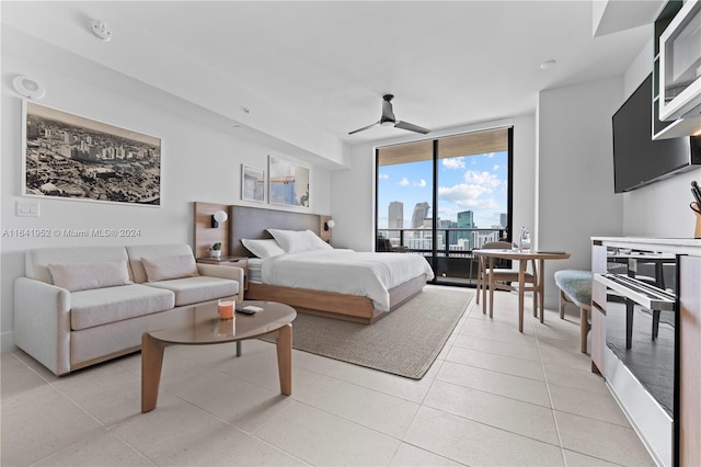 tiled bedroom with a wall of windows, ceiling fan, and access to exterior