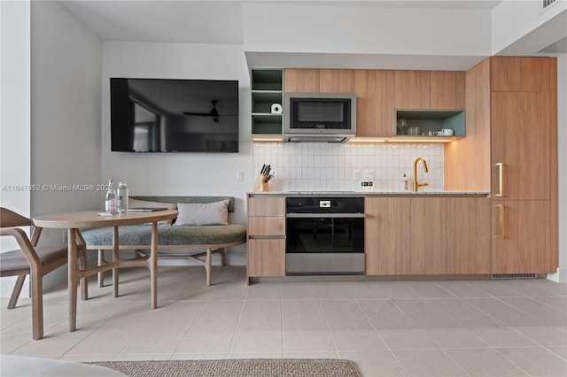 kitchen featuring light tile patterned flooring, sink, appliances with stainless steel finishes, light stone countertops, and tasteful backsplash