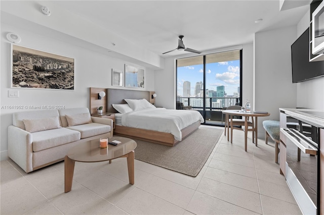 tiled bedroom with a wall of windows, ceiling fan, and access to exterior