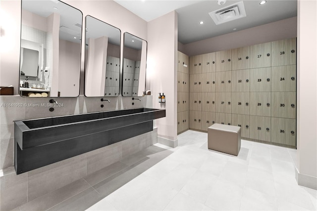 bathroom with a tub, vanity, tile patterned floors, and tile walls