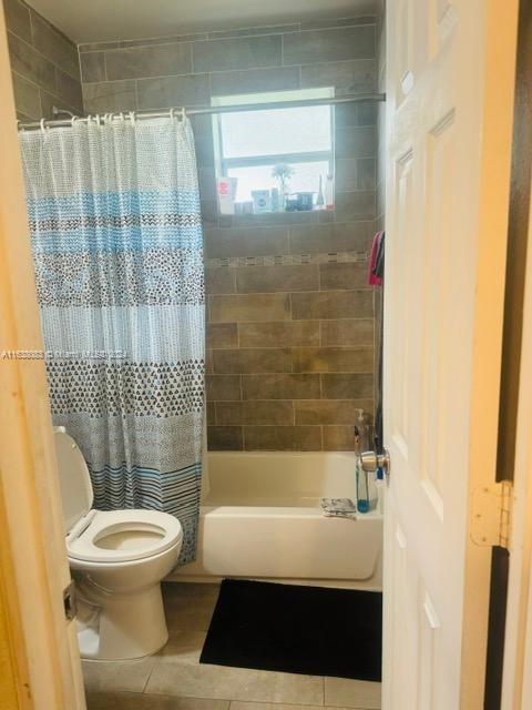 bathroom featuring shower / bath combo with shower curtain, tile patterned floors, and toilet