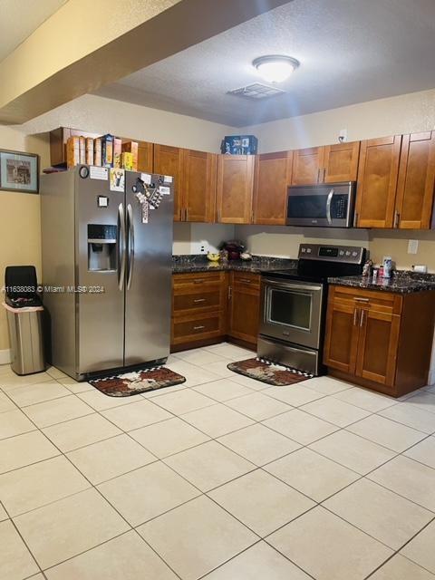 kitchen featuring dark stone countertops, stainless steel appliances, and light tile patterned floors