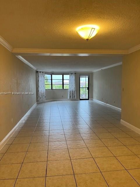 tiled empty room featuring crown molding and a textured ceiling