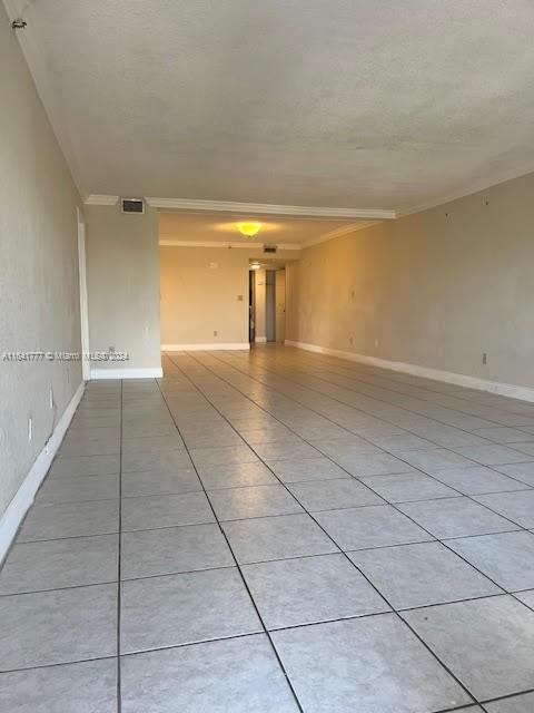 tiled empty room featuring crown molding