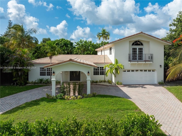 mediterranean / spanish-style home with a garage and a front lawn