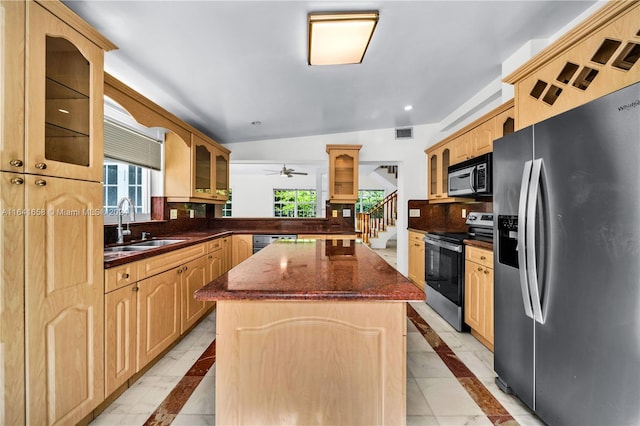 kitchen featuring a center island, light brown cabinets, stainless steel appliances, dark stone countertops, and sink