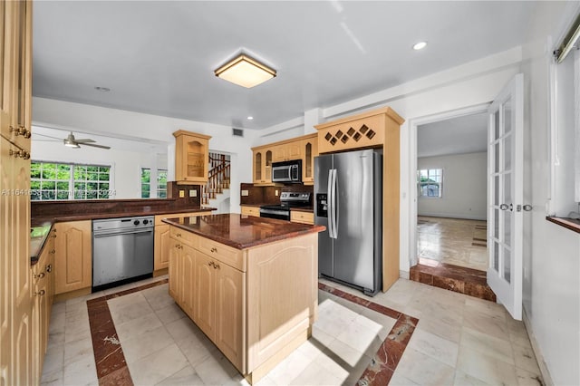 kitchen with light brown cabinetry, plenty of natural light, appliances with stainless steel finishes, and a kitchen island