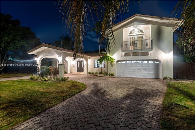 view of front of home featuring a balcony, a garage, and a yard