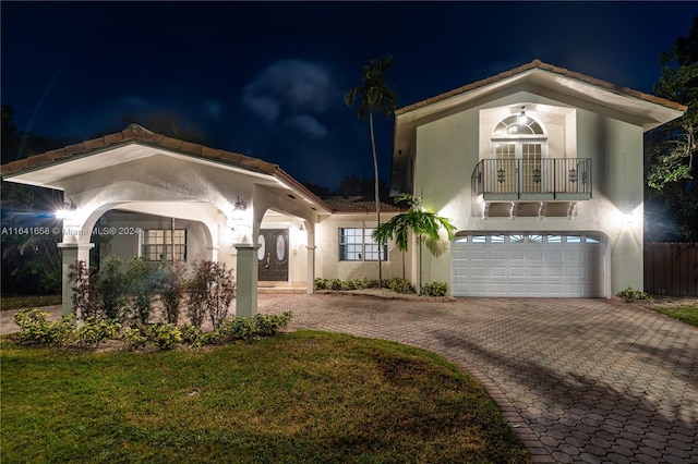 mediterranean / spanish home with a balcony, a lawn, and a garage