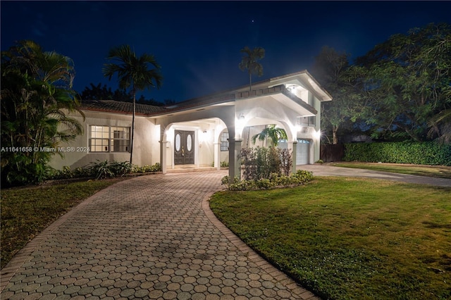 view of front of home with a garage and a lawn