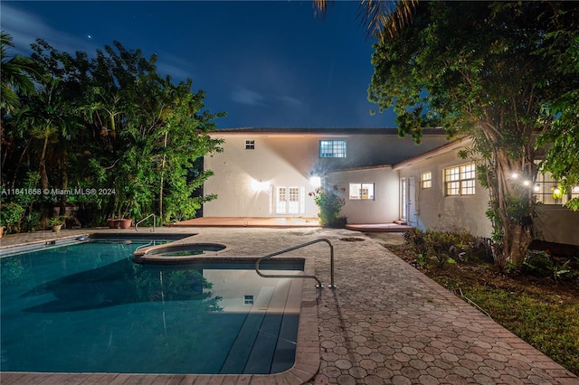 pool at twilight featuring an in ground hot tub and a patio area