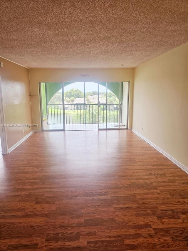 unfurnished room featuring wood-type flooring, a wealth of natural light, and a textured ceiling