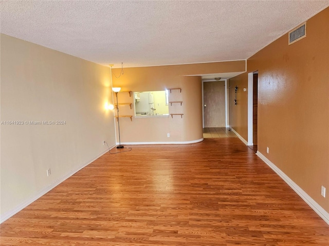 empty room featuring a textured ceiling and light hardwood / wood-style floors