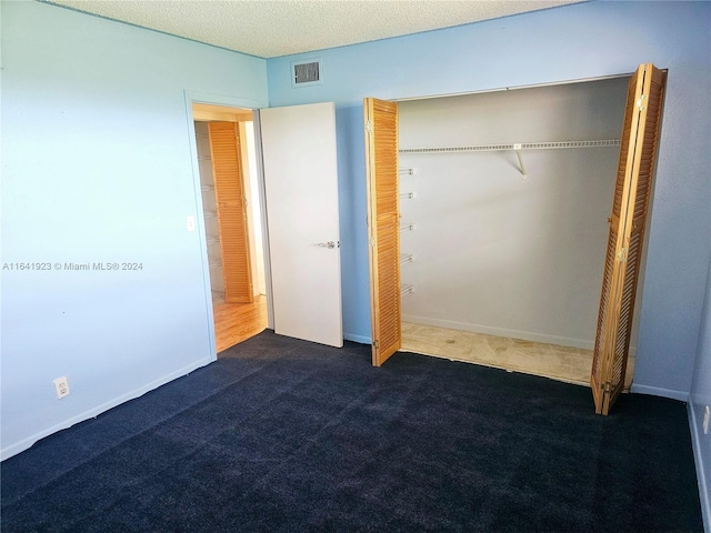 unfurnished bedroom with a textured ceiling, a closet, and carpet floors