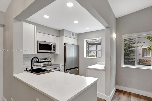 kitchen featuring appliances with stainless steel finishes, plenty of natural light, tasteful backsplash, and light hardwood / wood-style floors