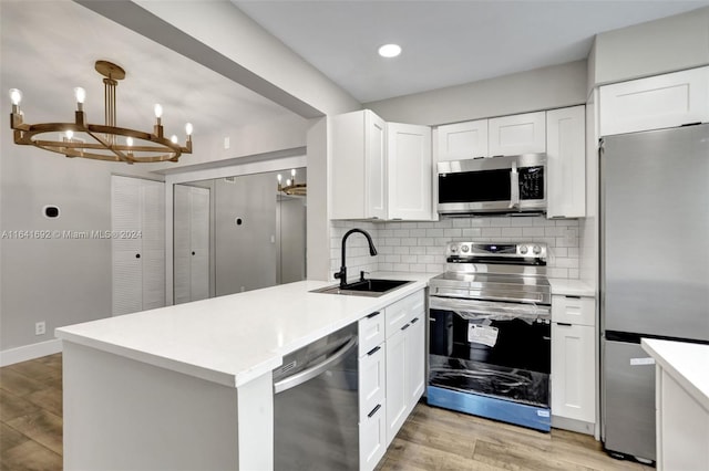 kitchen with decorative backsplash, appliances with stainless steel finishes, a notable chandelier, sink, and light hardwood / wood-style floors