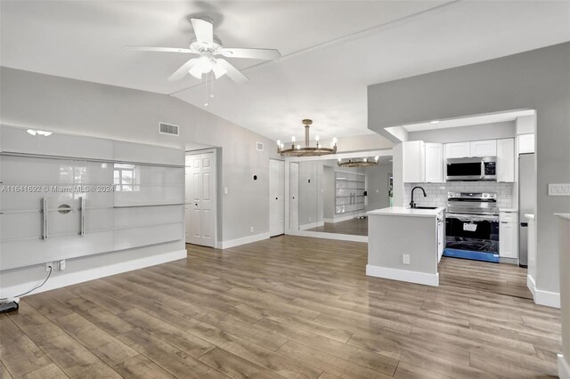 unfurnished living room with light wood-type flooring, vaulted ceiling, ceiling fan with notable chandelier, and sink