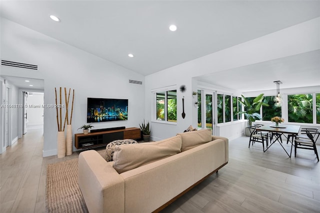 living room featuring lofted ceiling and light hardwood / wood-style floors