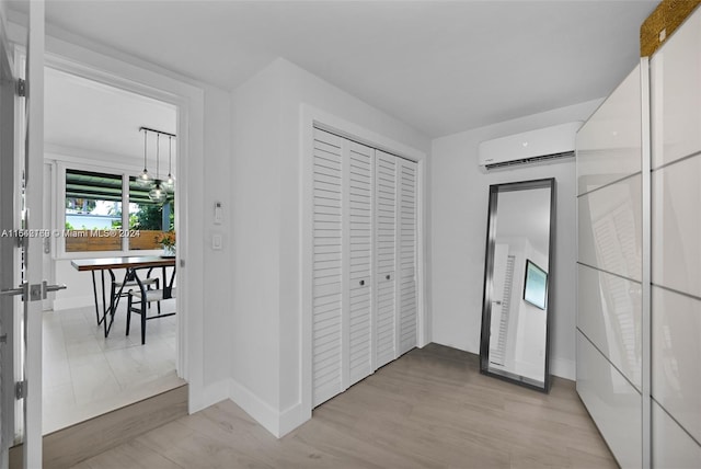 bedroom featuring a wall mounted AC, light hardwood / wood-style floors, and a closet