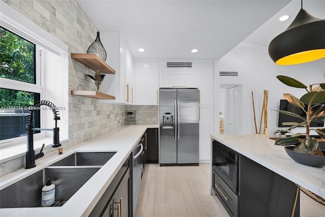 kitchen featuring decorative backsplash, white cabinetry, appliances with stainless steel finishes, decorative light fixtures, and sink