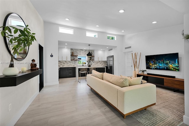 living room featuring sink, a towering ceiling, and a healthy amount of sunlight