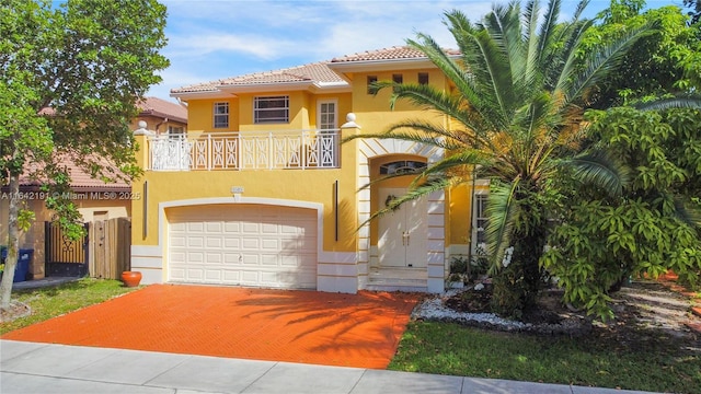 mediterranean / spanish house featuring stucco siding, a tiled roof, a balcony, driveway, and a garage