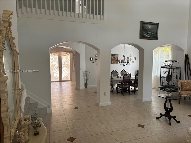 interior space with a high ceiling, arched walkways, and light tile patterned floors
