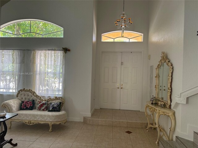 entryway featuring a high ceiling, light tile patterned floors, and an inviting chandelier