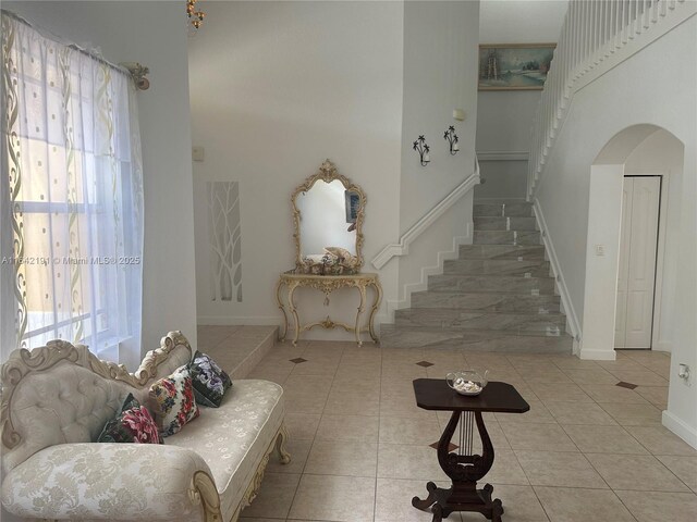 foyer featuring a towering ceiling, tile patterned floors, and a notable chandelier