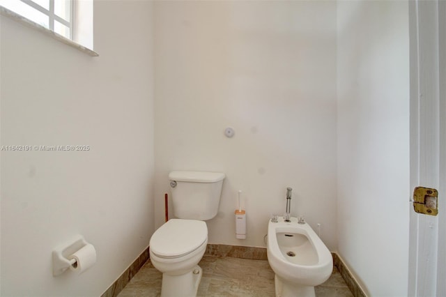 half bathroom featuring a bidet, toilet, and baseboards