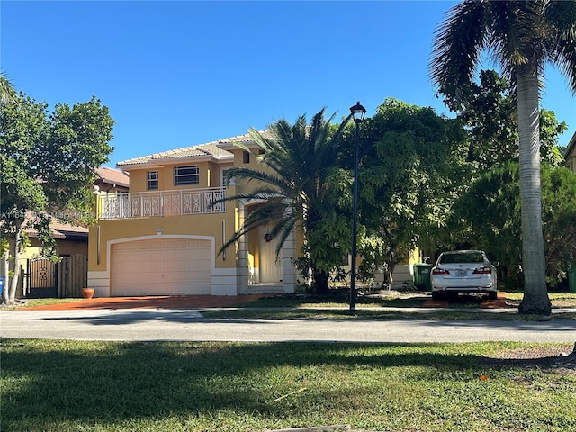 view of front of house with driveway, a garage, a balcony, a tiled roof, and stucco siding