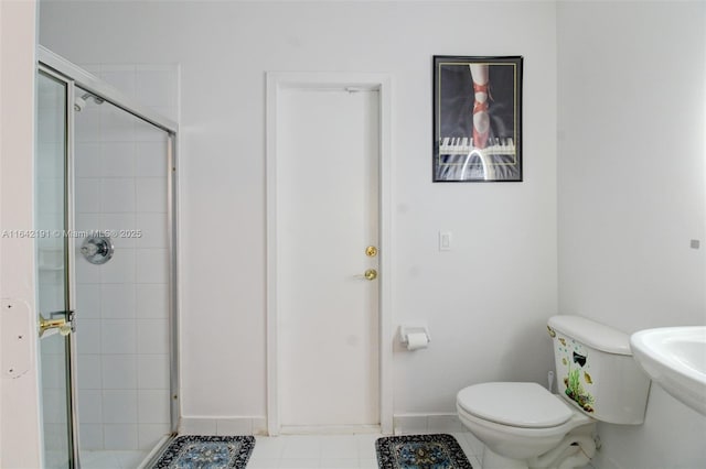 full bathroom with a stall shower, tile patterned floors, toilet, a sink, and baseboards