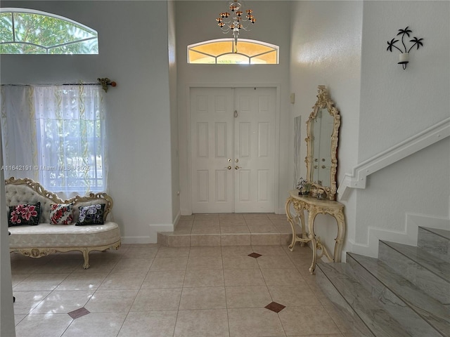 tiled foyer entrance featuring baseboards and stairway