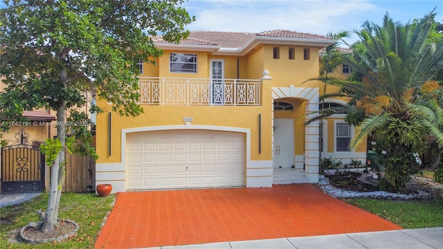 mediterranean / spanish house featuring an attached garage, a balcony, a tiled roof, a gate, and stucco siding