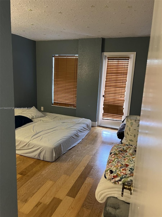 bedroom with a textured ceiling and light hardwood / wood-style floors