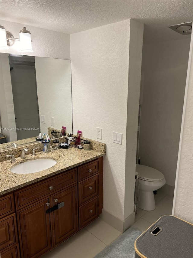 bathroom featuring tile patterned floors, vanity, toilet, and a textured ceiling