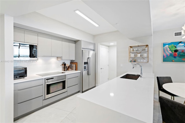 kitchen with light tile patterned flooring, gray cabinets, backsplash, stainless steel appliances, and sink