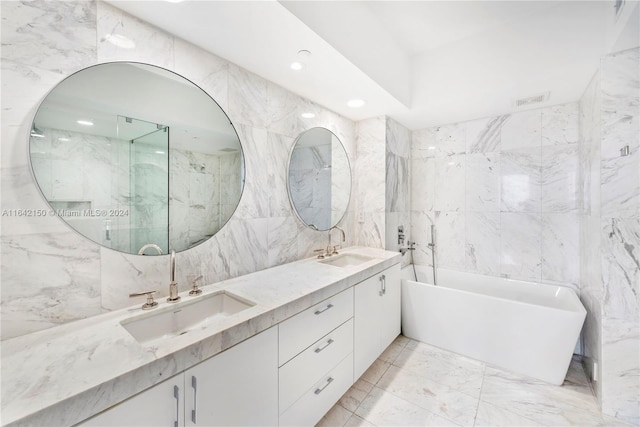 bathroom with a washtub, tile walls, tile patterned floors, and dual vanity