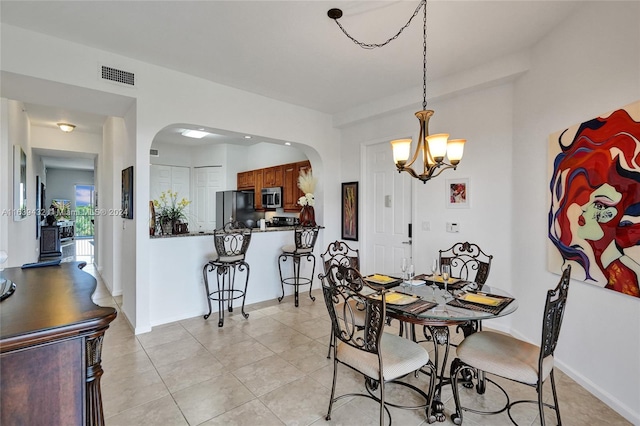 tiled dining room with a chandelier