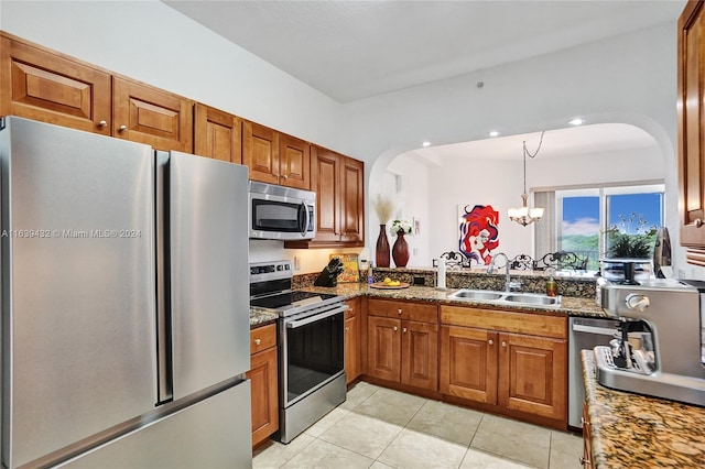 kitchen with an inviting chandelier, appliances with stainless steel finishes, dark stone countertops, light tile patterned floors, and sink