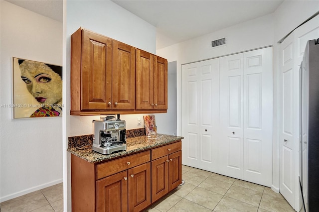 kitchen featuring light tile patterned floors and dark stone counters