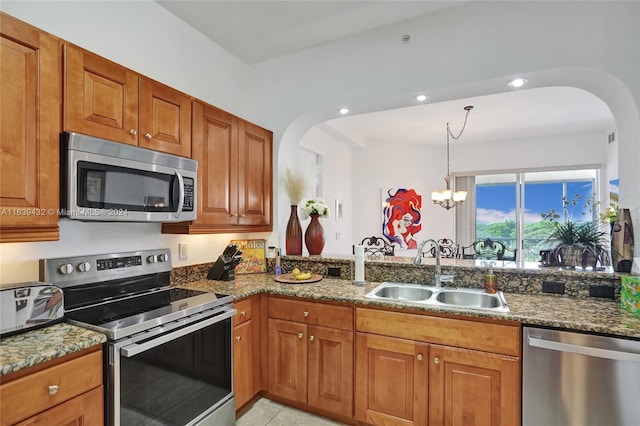 kitchen with appliances with stainless steel finishes, sink, stone counters, and a chandelier