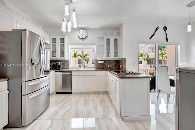 kitchen with a sink, a peninsula, white cabinetry, and stainless steel appliances