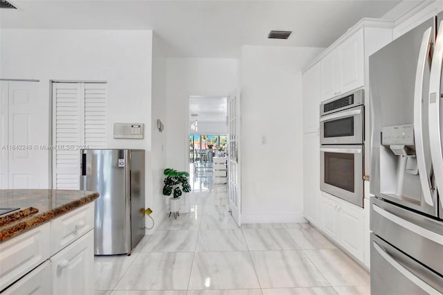 kitchen featuring dark stone counters, white cabinets, visible vents, and appliances with stainless steel finishes