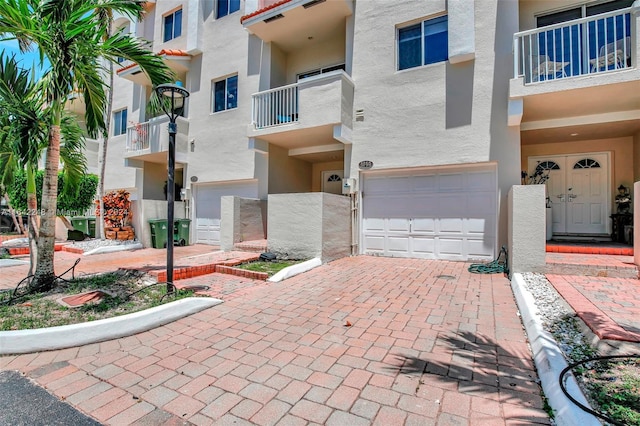 exterior space with stucco siding, decorative driveway, and an attached garage