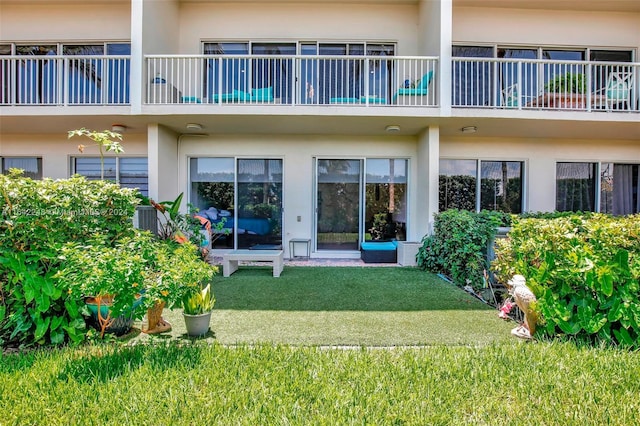 back of property with stucco siding and a lawn