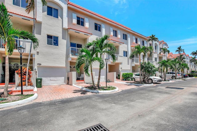 view of building exterior featuring decorative driveway, a residential view, and an attached garage