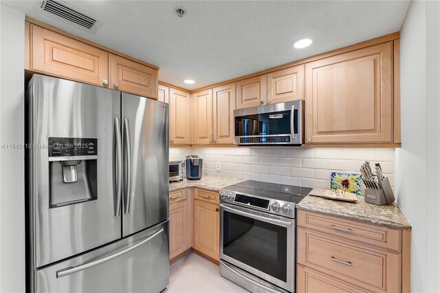 kitchen featuring appliances with stainless steel finishes, light stone countertops, and light brown cabinets