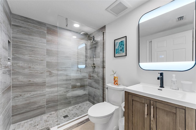 bathroom featuring toilet, vanity, and a tile shower