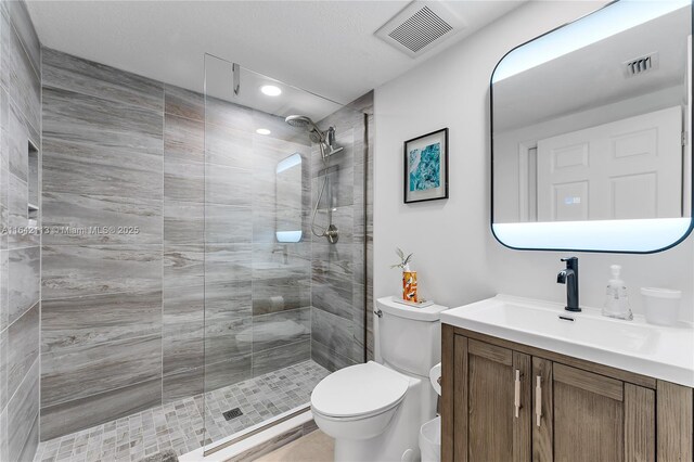 bathroom with tiled shower, vanity, and toilet